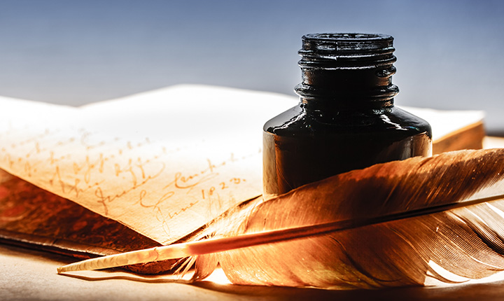 Old parchment with feather pen and ink bottle