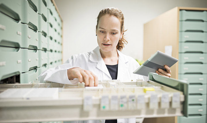 Woman in lab coat searching for medicines in a drawer