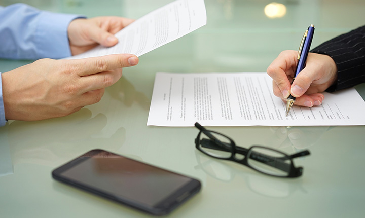 Two people reading and signing contracts