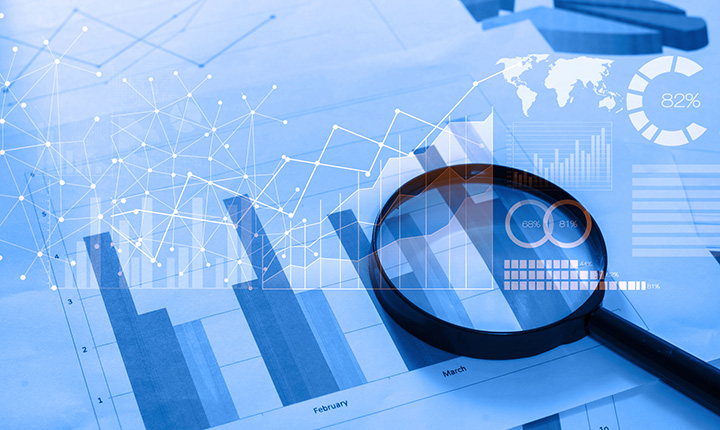 Magnifying glass and graphs lying on a table with data analytics superimposed