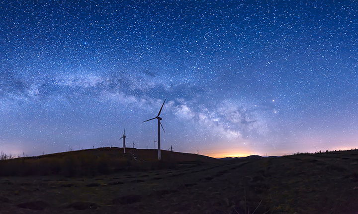 Starry night landscape with windmills on the horizon