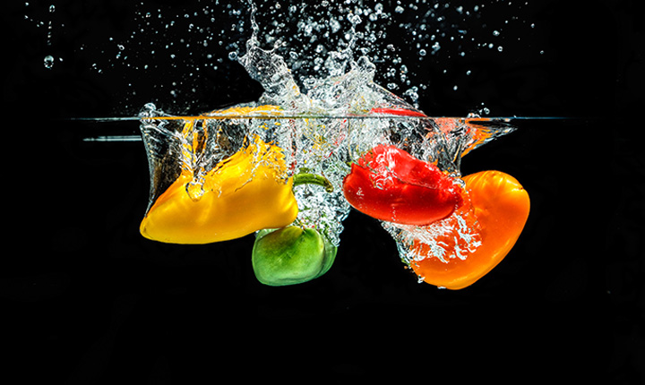 Bell peppers being dropped into water (slow motion capture black background)