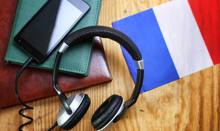 Headphones, iphone resting on notebook with french flag on table
