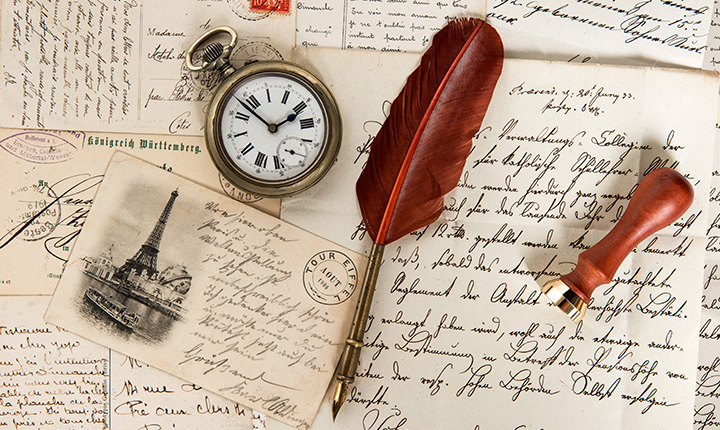 Notes with hand written messages with a feather pen and pocket watch sitting on top