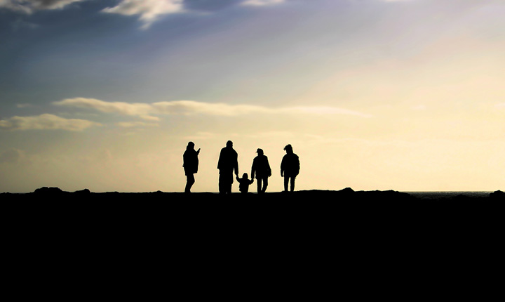 A family with a young child silhouetted against a bright sky