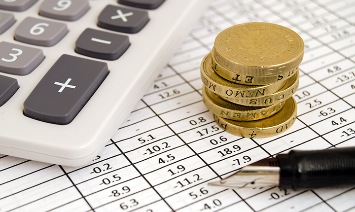 Close up of calculator, one euro coins and balance sheet