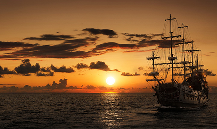 A tall ship sailing into the sunset