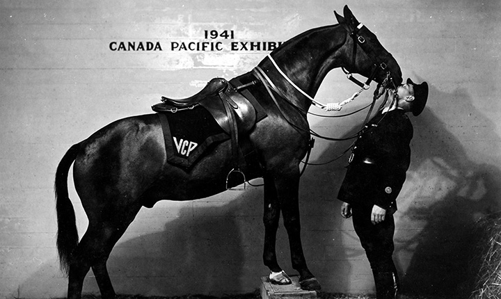 A black and white image of a horse kissing an officer