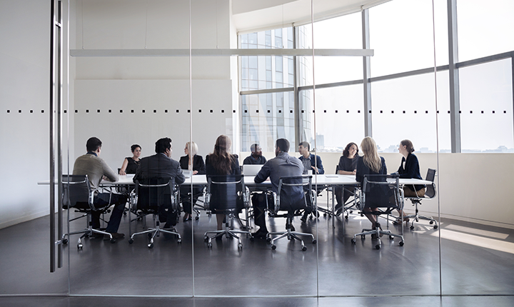 Business meeting taking place in a glass walled boardroom