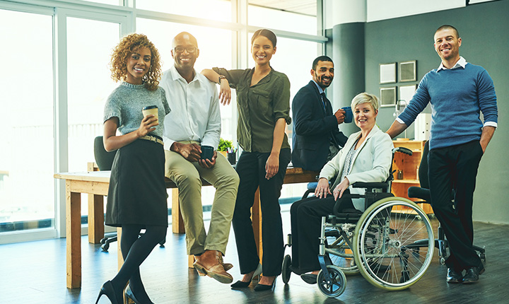 A group of people with a range of mobility standing in a sunny office