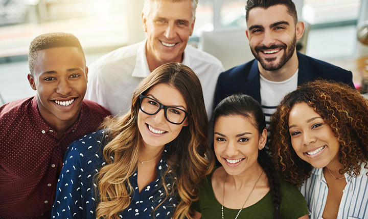 A multi-ethnic group of business people smiling and standing in an office