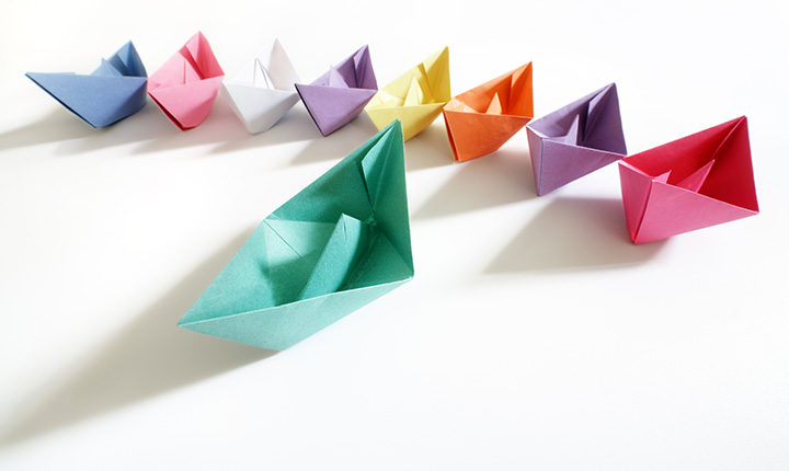 Colourful paper boats sitting in a line resembling leadership