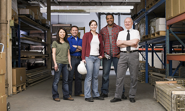 A diverse group of workers standing in front of a warehouse