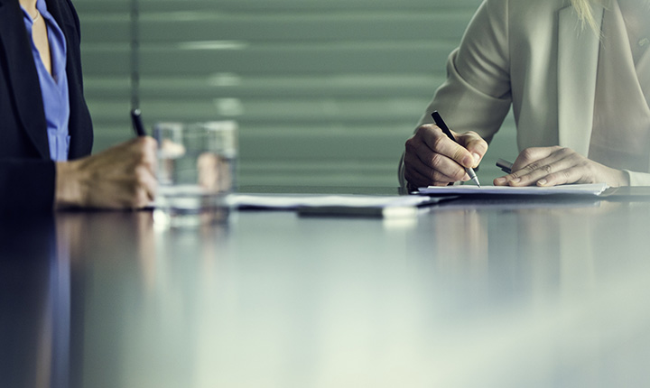 Two business people signing paperwork