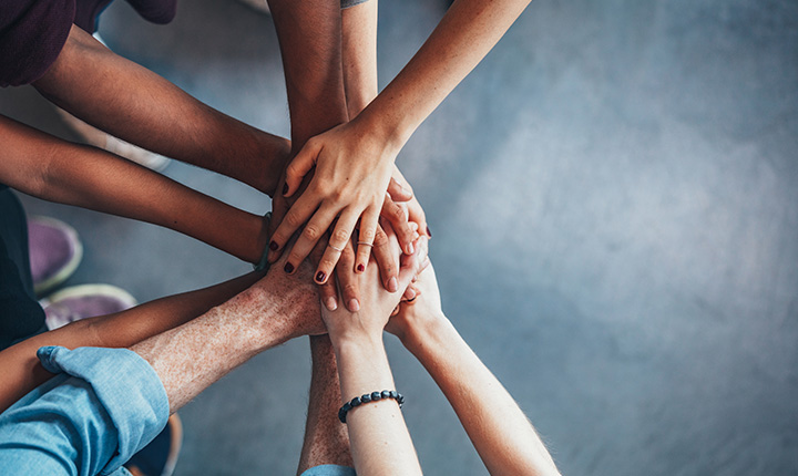 A diverse group of hands piling together to signify teamwork