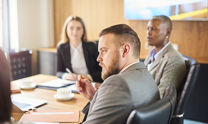 A group of people in a boardroom reviewing documents