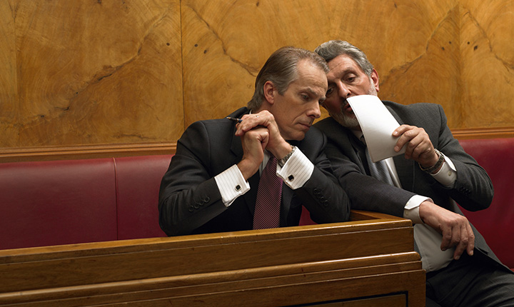 Two men in business suits whispering in court