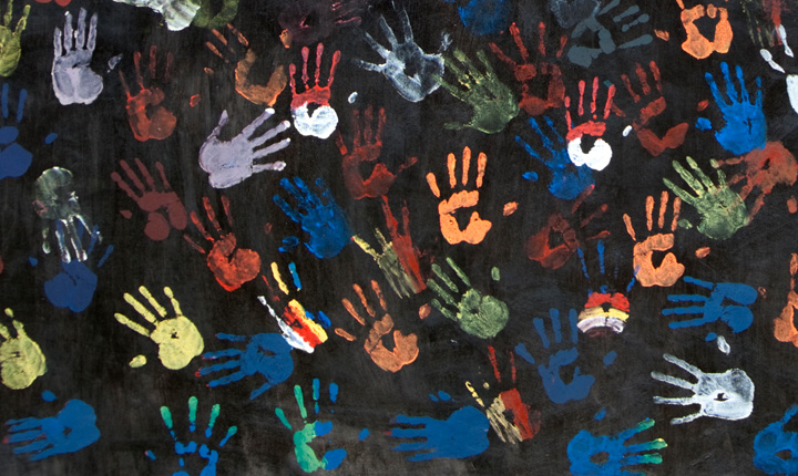 Hand prints in various paint colours on a black background