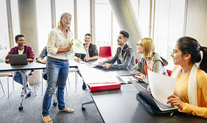 College classroom with mature female teacher and young multi ethnic students