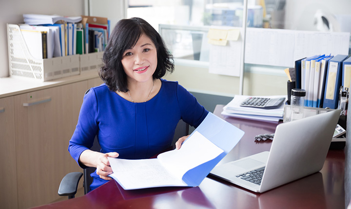 Woman sitting at a desk in an office reading paperwork