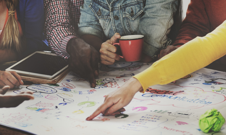 A group of people working at a table writing and collaborating together